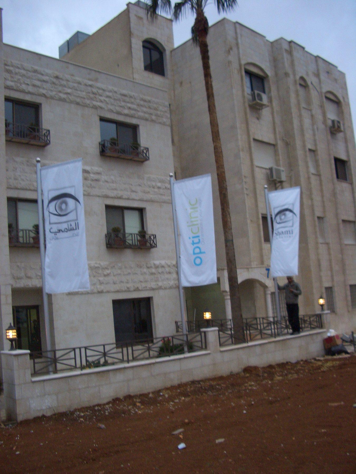 White flag banners with the logo hung on the front of a medical centre building