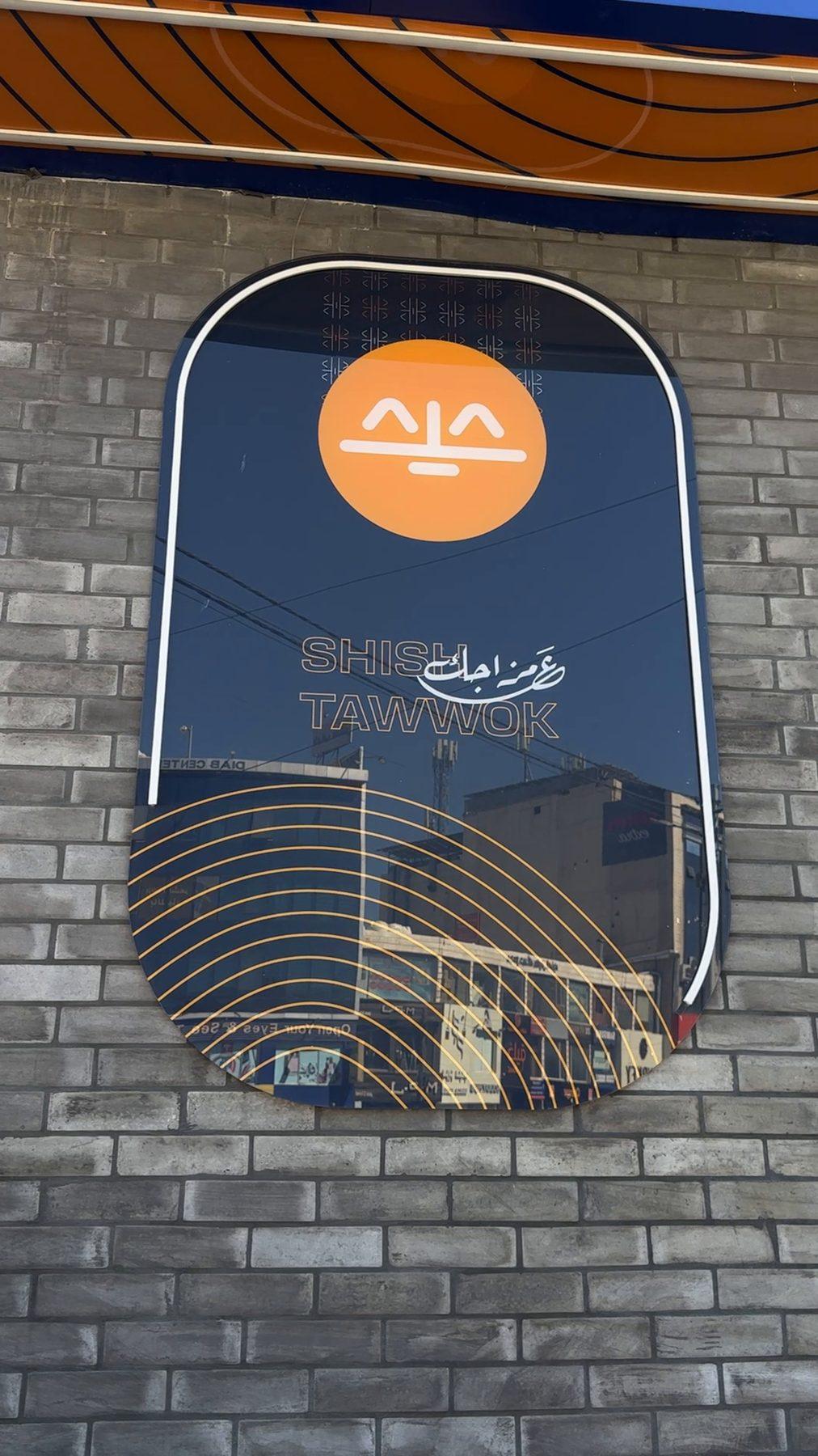 The framed logo panel on the brick wall.