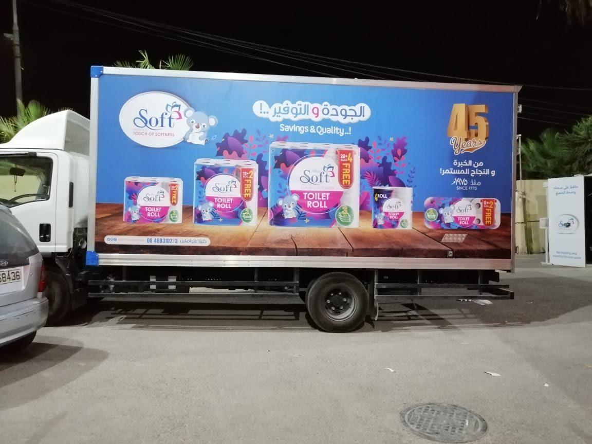Box truck with a large side graphic of products and a 45-years mark, photographed at night