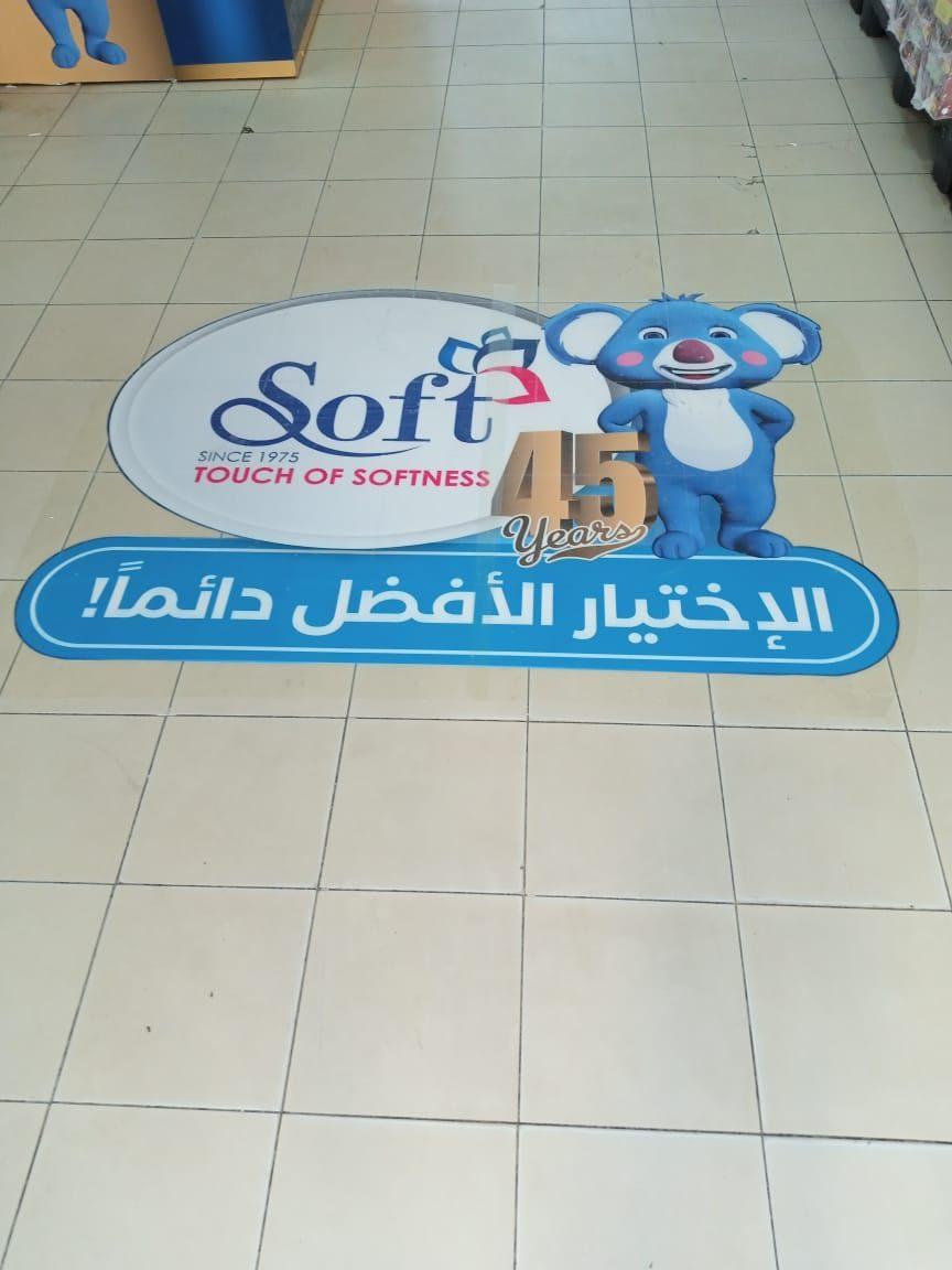Floor sticker with a logo, mascot and Arabic slogan on a tiled floor