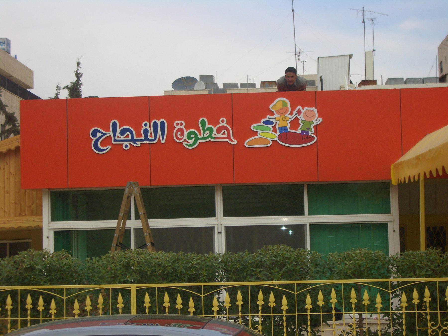 Orange-red facade with Arabic lettering and logo above the windows