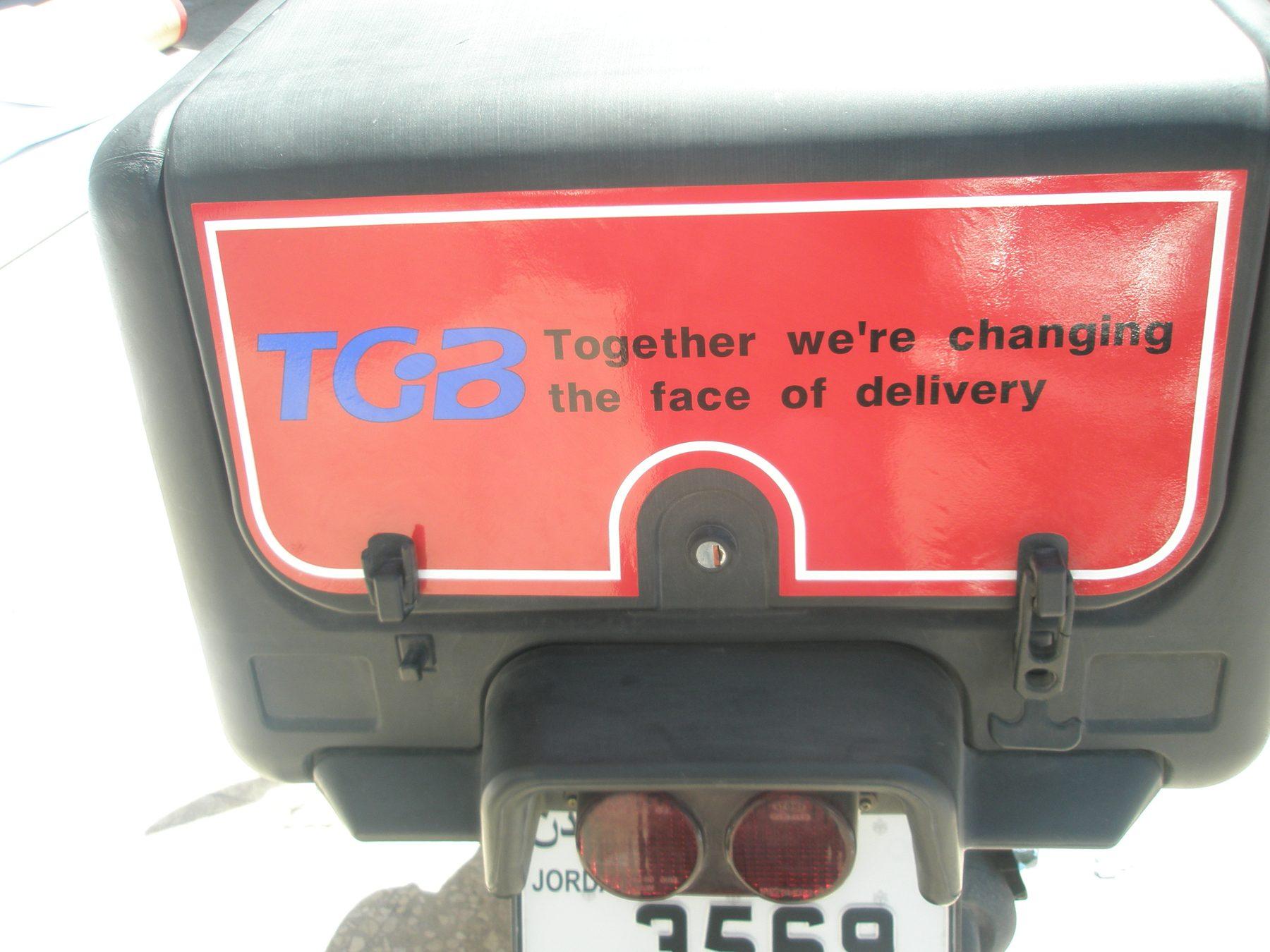 Rear of a red scooter delivery box with a white-bordered panel and a slogan.