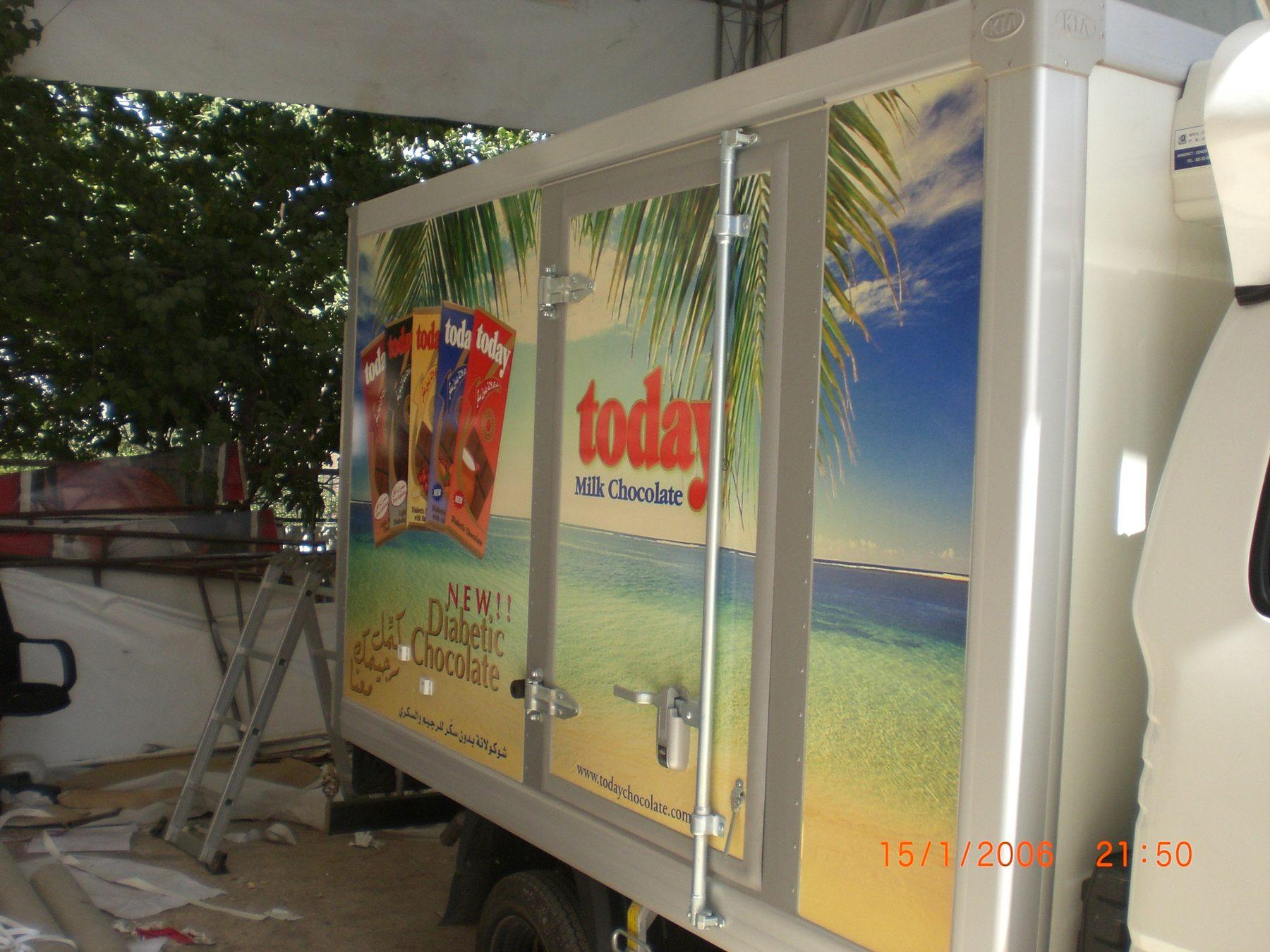 White box truck with a beach-scene graphic and product panels on its side.