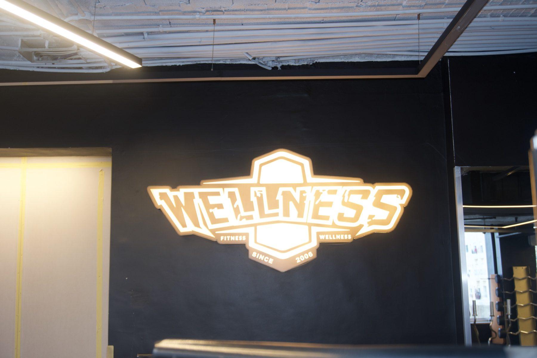 Illuminated logo on a dark wall under ceiling lights