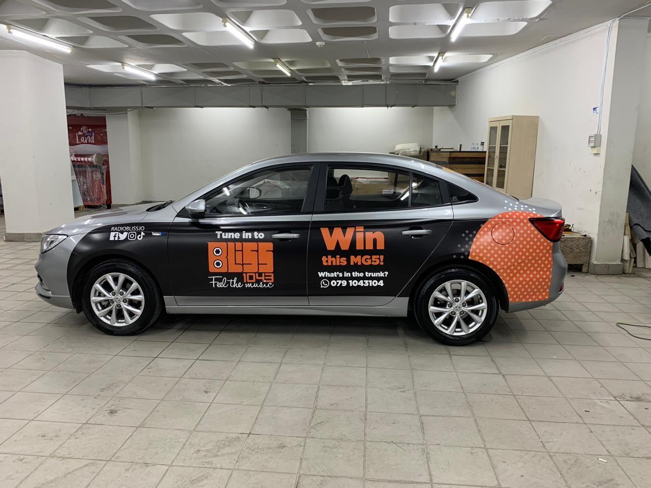 Grey sedan with orange and black side graphics in an indoor garage.