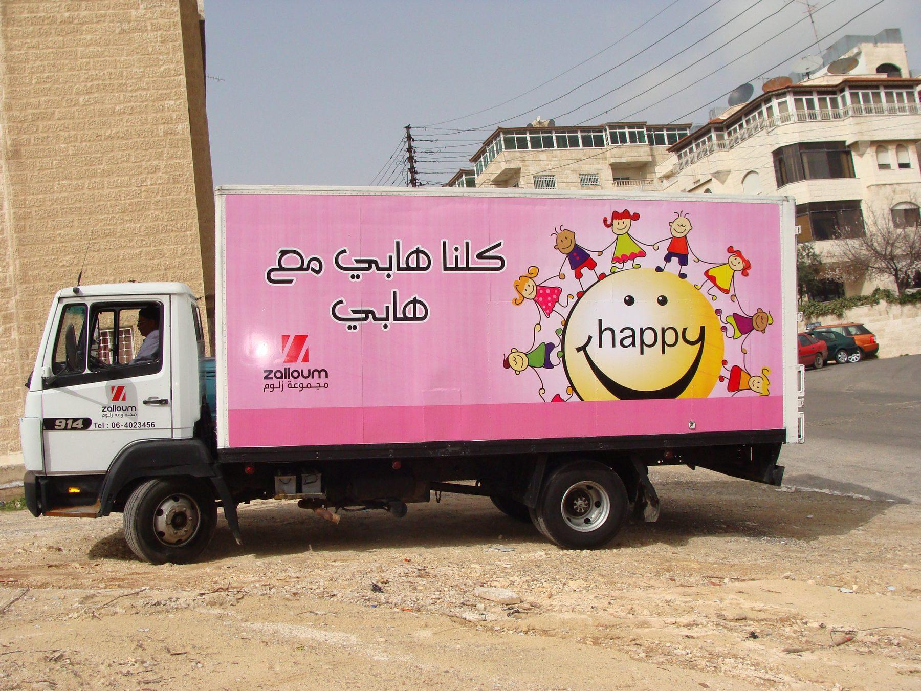 Side view of a box truck with pink panel and character graphic