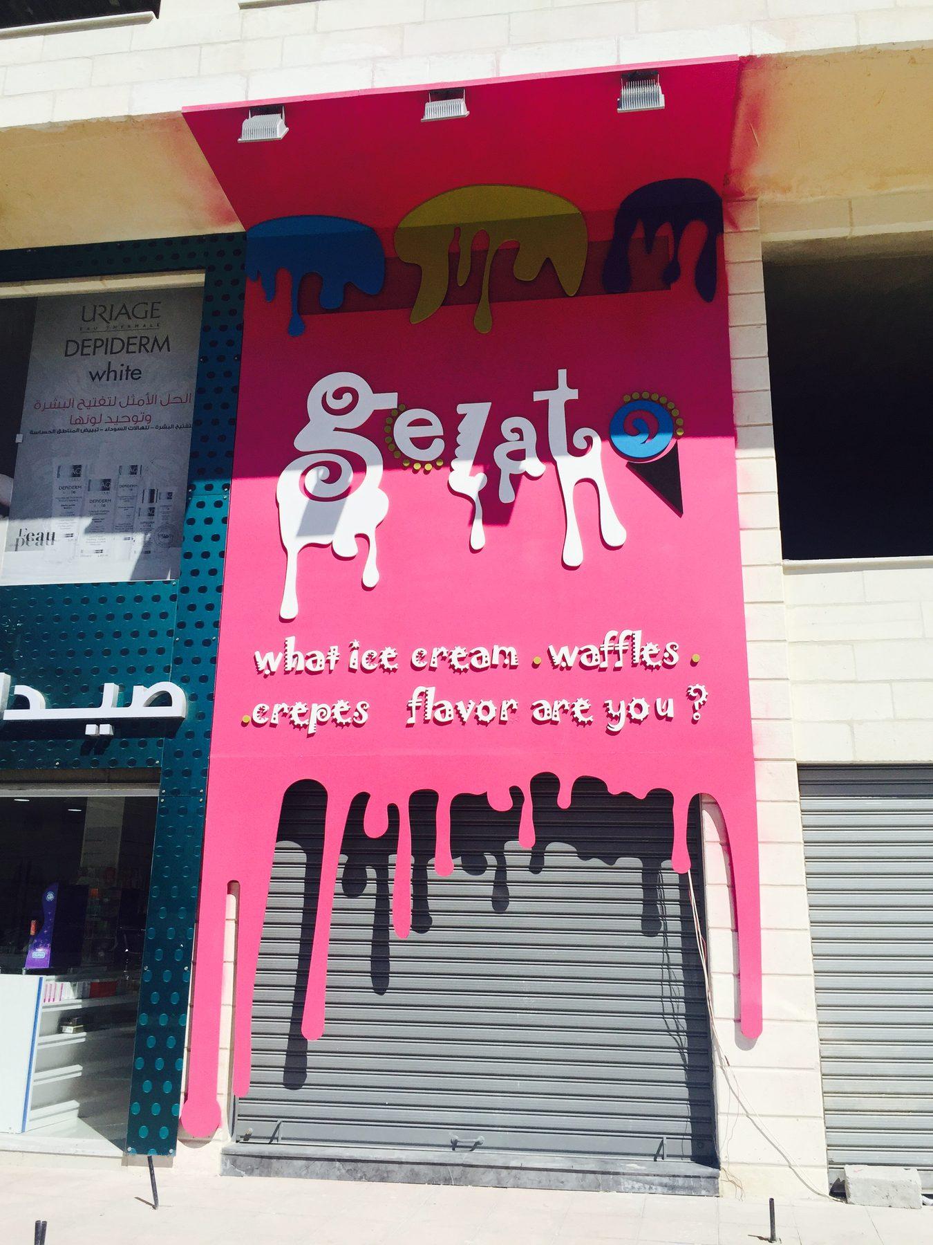 Pink shopfront wall graphic with white lettering and drips