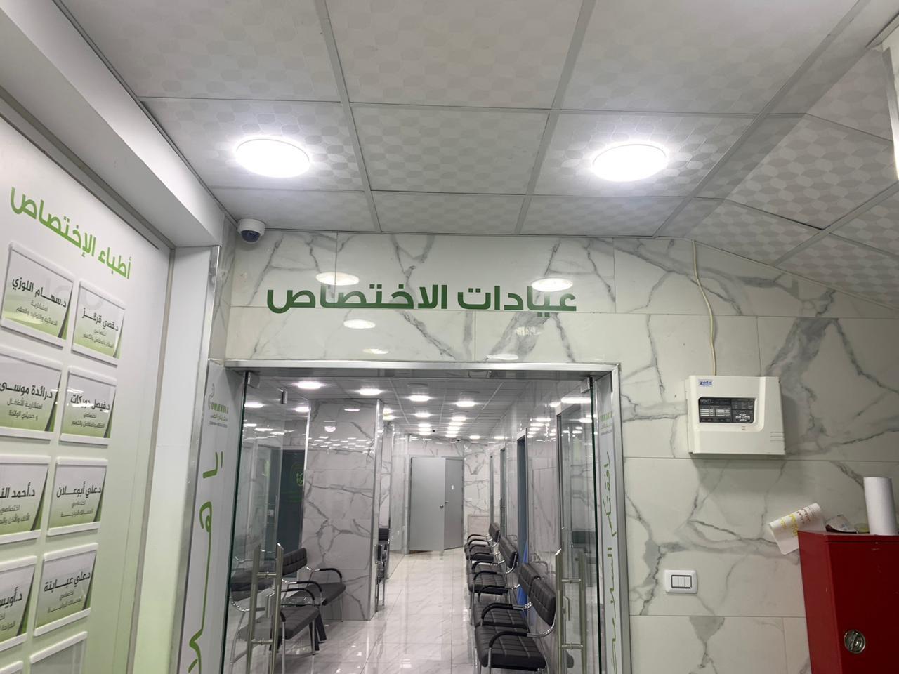 Corridor with a green Arabic sign for specialty clinics and framed panels