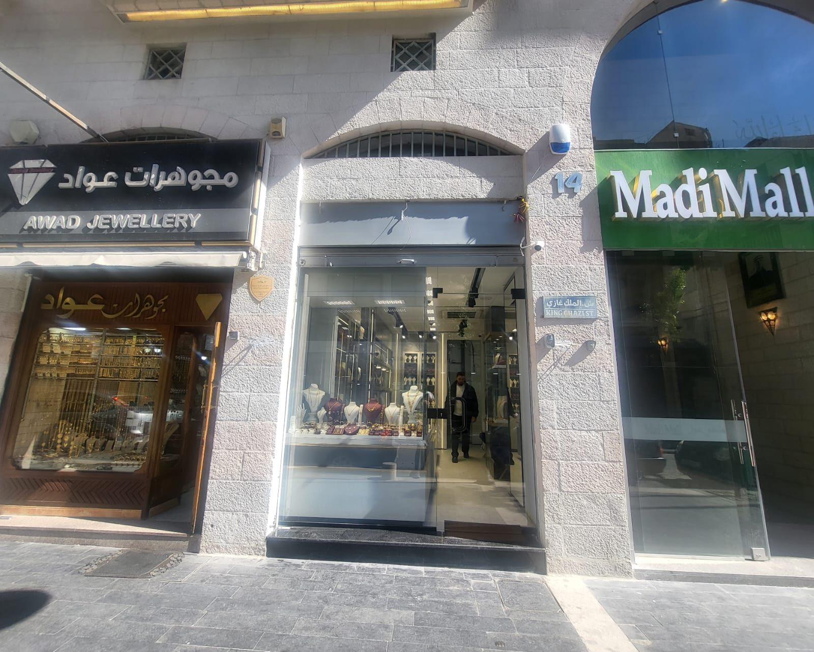 Black fascia sign above a stone-clad jewellery storefront