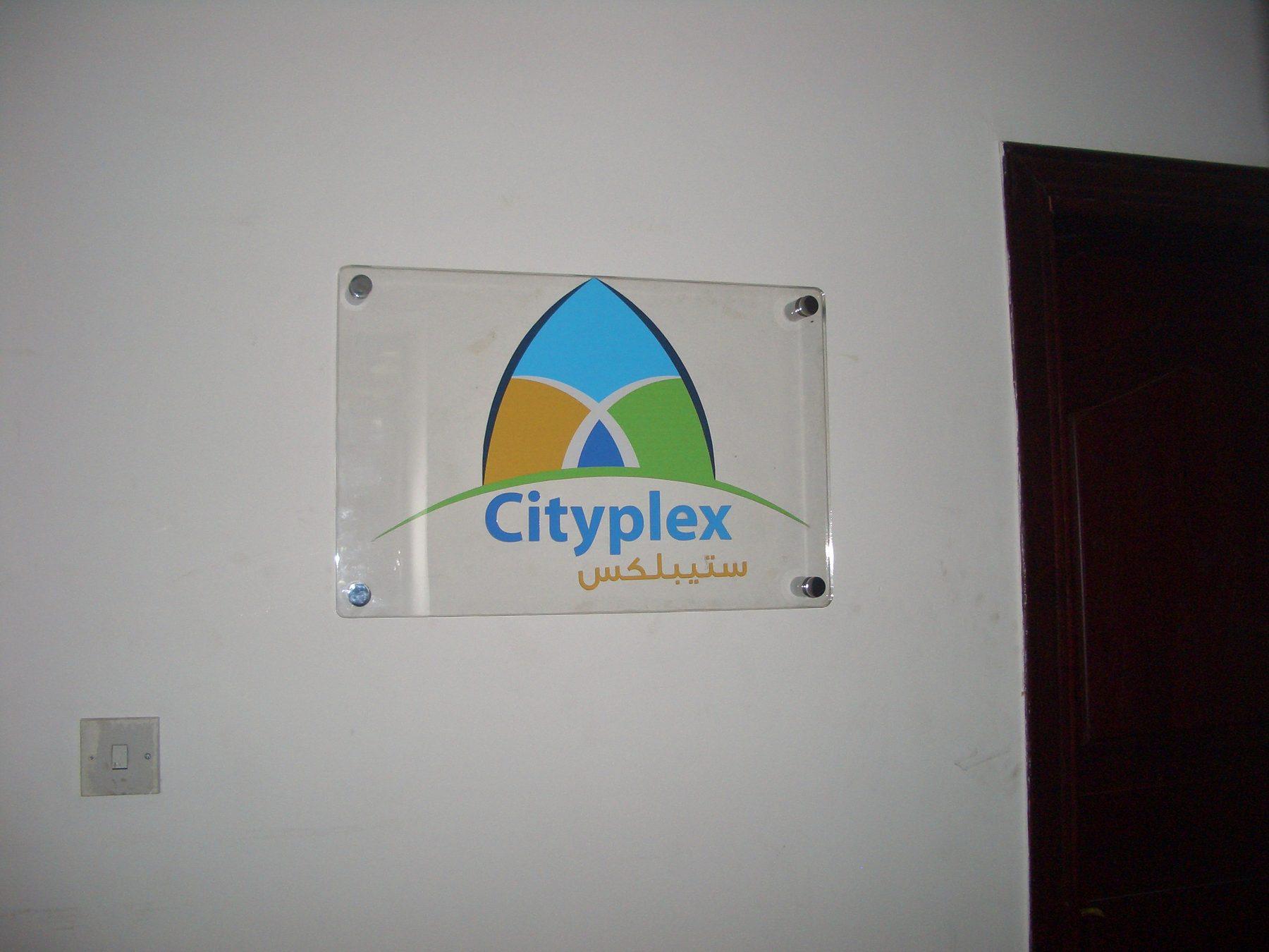 Clear acrylic logo plaque with a full-colour logo mounted on a white wall.