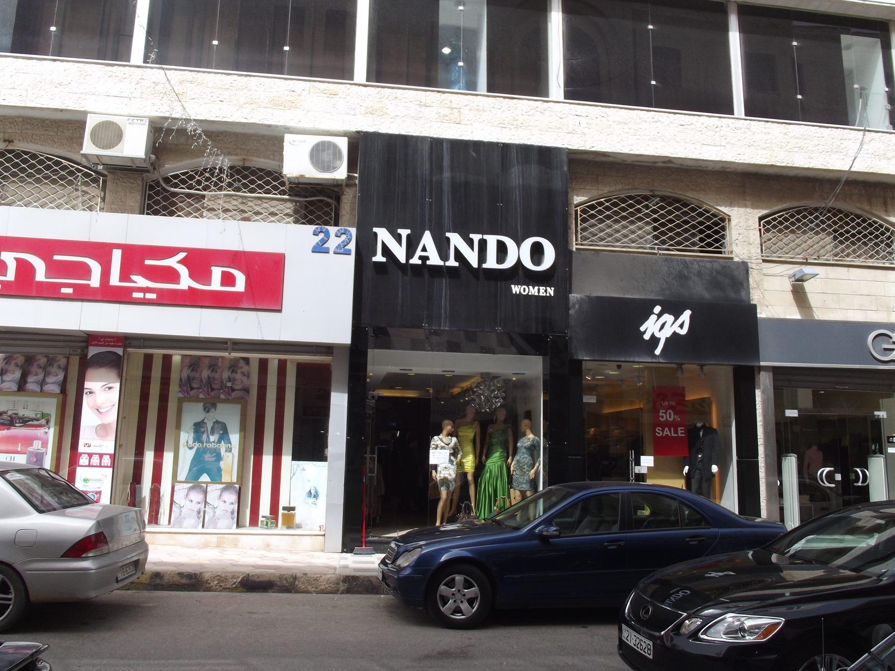Dark fascia with raised white lettering above a boutique front, in daylight.