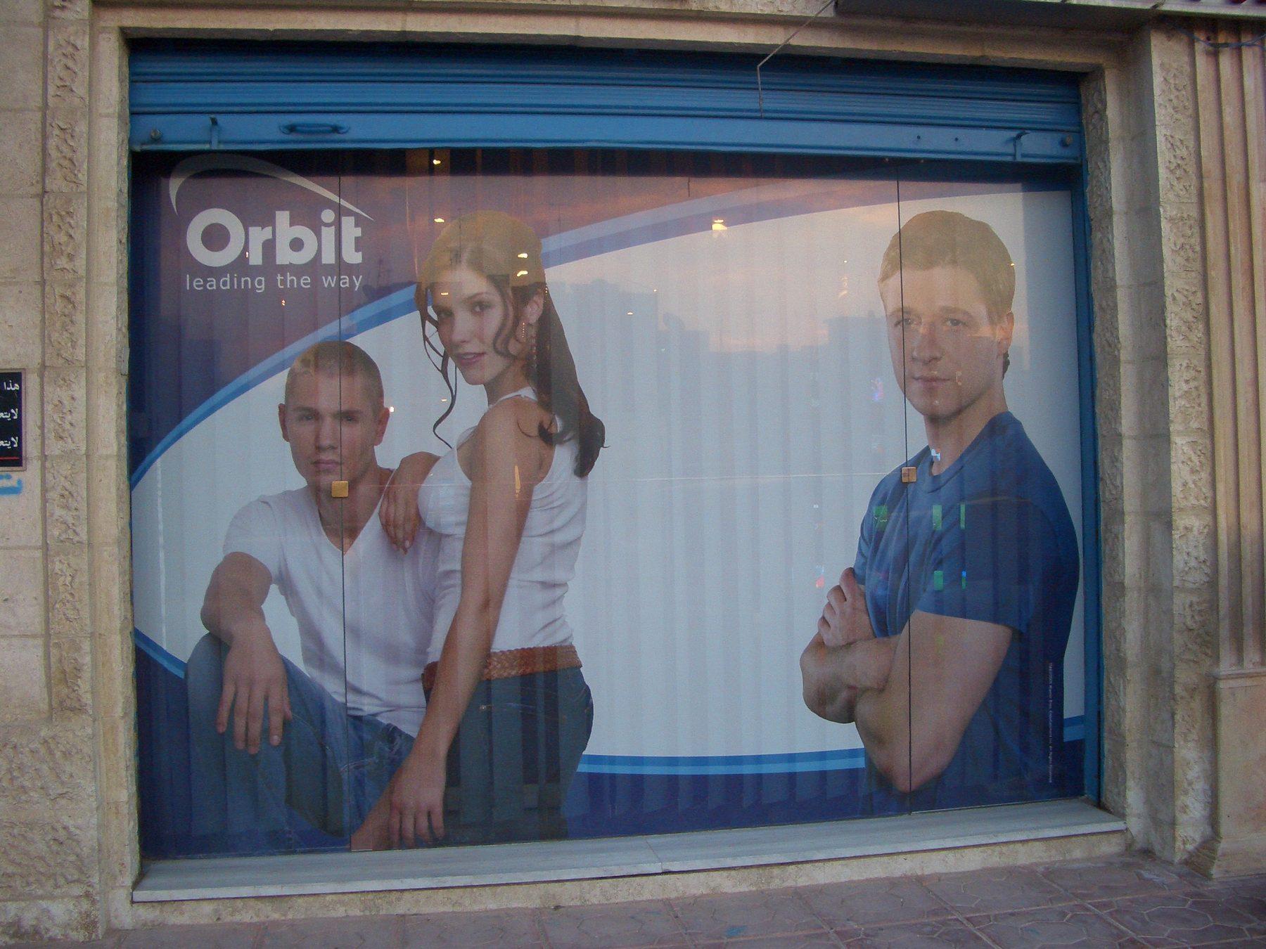 Printed window graphic showing two models on a roller shutter shopfront.