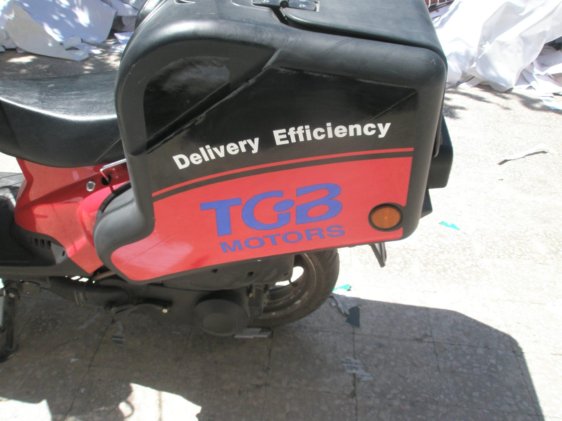 Red and black scooter delivery box with the Delivery Efficiency graphic and a logo.